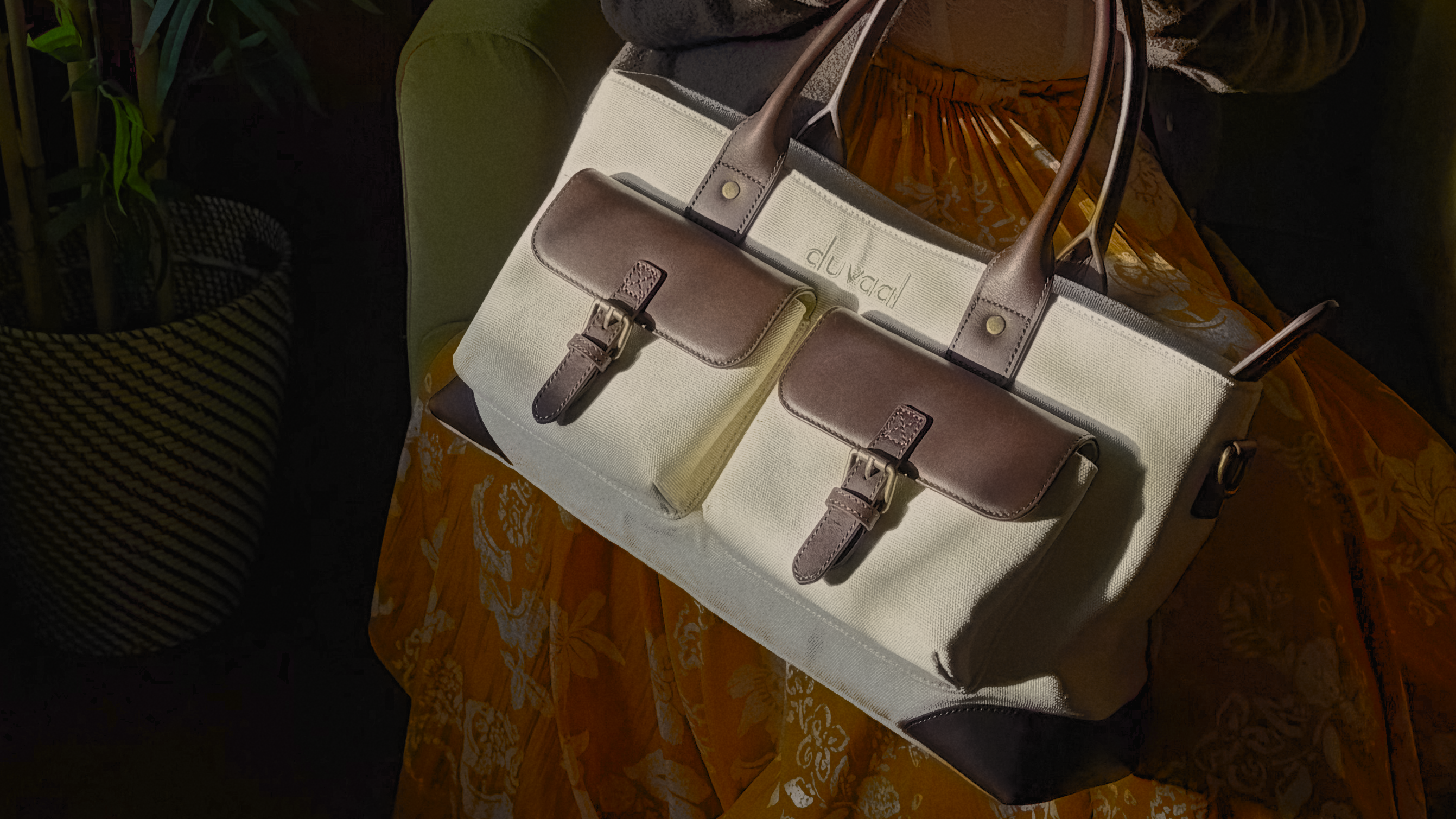 Person holding a white handbag with brown accents in a cozy indoor setting.